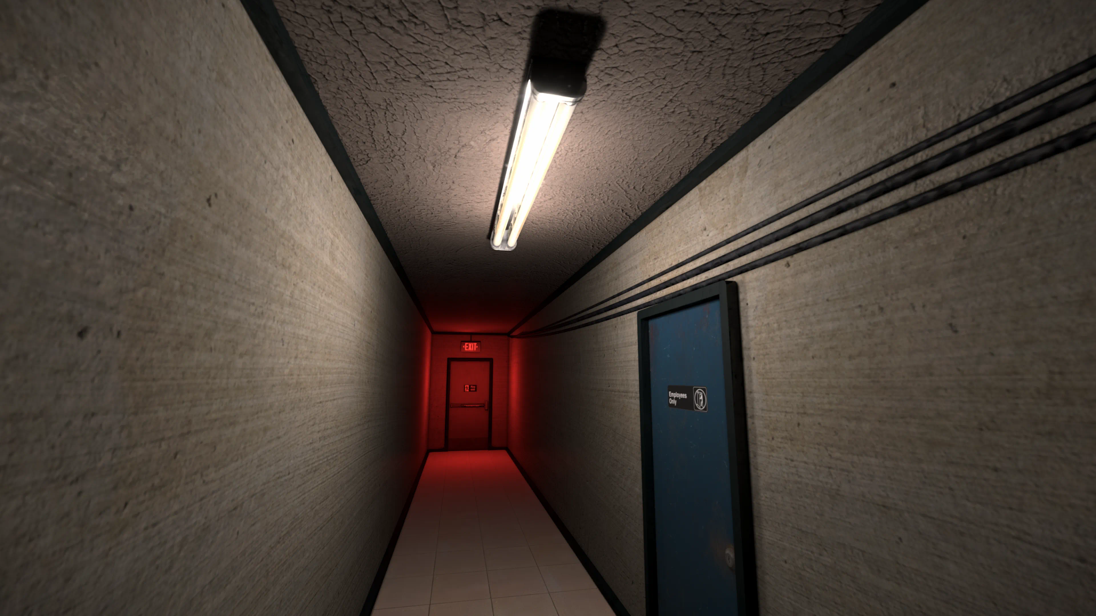A narrow concrete corridor with an Employees Only door and a red-lit exit at the far end